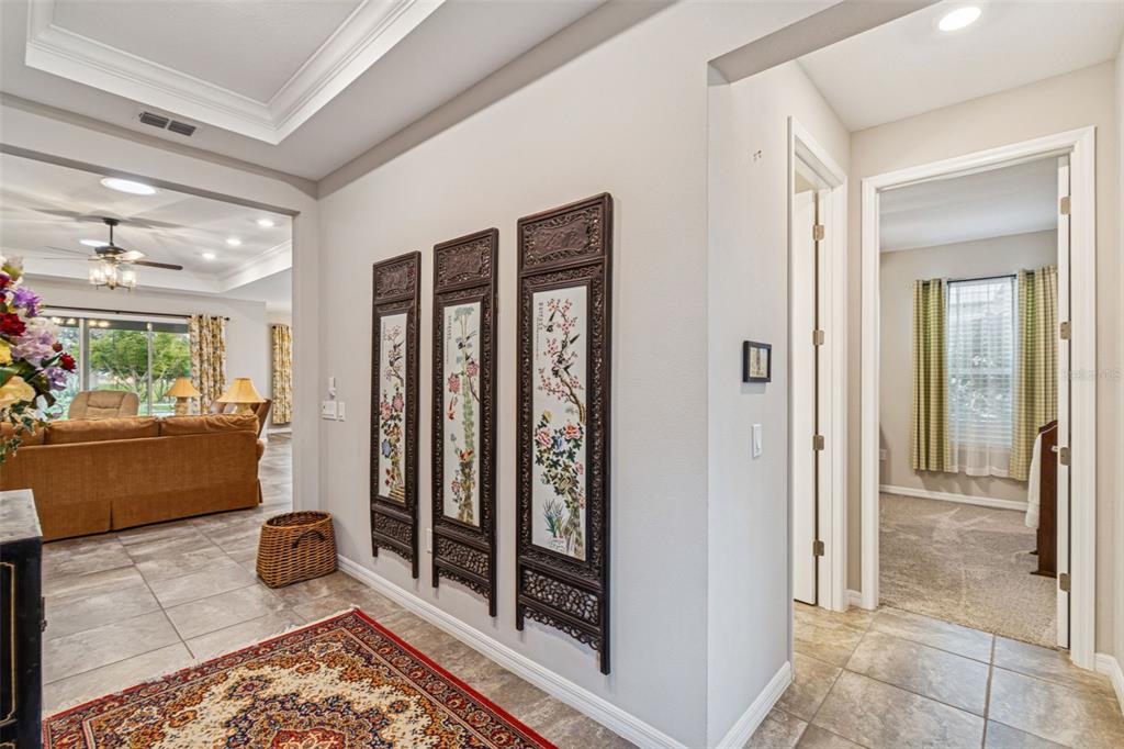 A hallway with tiled floors features three decorative wall panels and leads to a living room — 795 AVIARA LANE, KISSIMMEE, FL