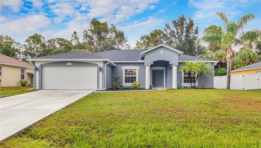 A single-story gray house with a two-car garage, white columns, and a front lawn — 2038 MINCEY TERRACE, NORTH PORT, FL