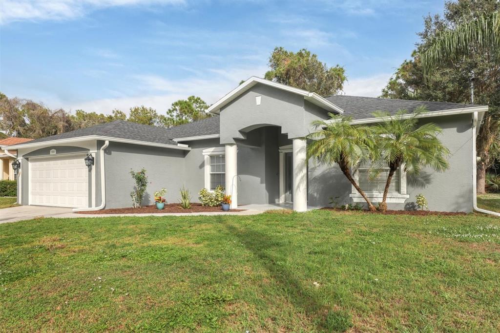A gray single-story house with a two-car garage, white columns, and a front lawn — 2038 MINCEY TERRACE, NORTH PORT, FL
