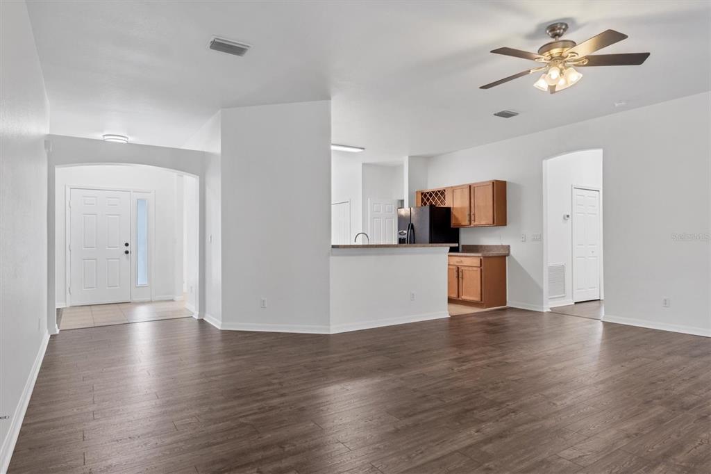 A living room with wood-look flooring leads to an open kitchen with wood cabinets — 2038 MINCEY TERRACE, NORTH PORT, FL