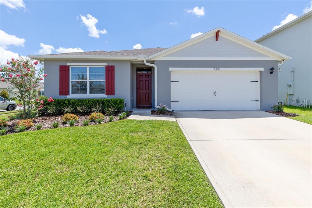A single-story gray house with a two-car garage, red shutters, and a front lawn — 2001 APALACHICOLA LANE, SANFORD, FL