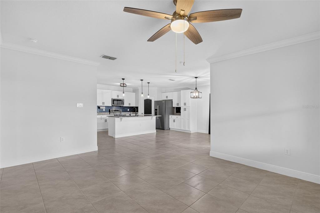 A spacious, open-concept kitchen features white cabinetry, stainless steel appliances, and large floor tiles — 2001 APALACHICOLA LANE, SANFORD, FL