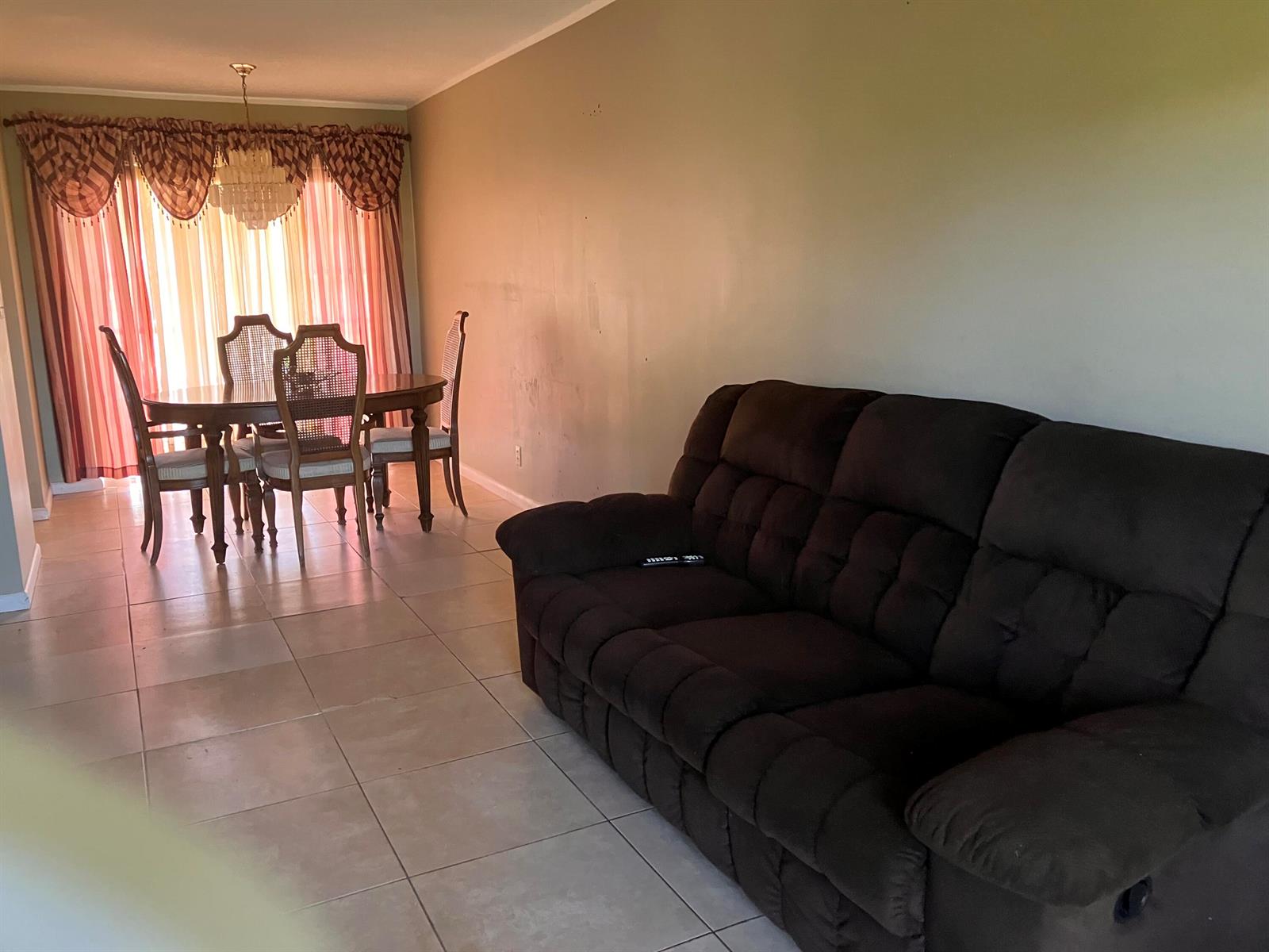 A living room with a dark brown sofa and an adjacent dining area with curtains — 17 Golfs Edge # D, West Palm Beach FL 33417, WEST PALM BEACH, FL