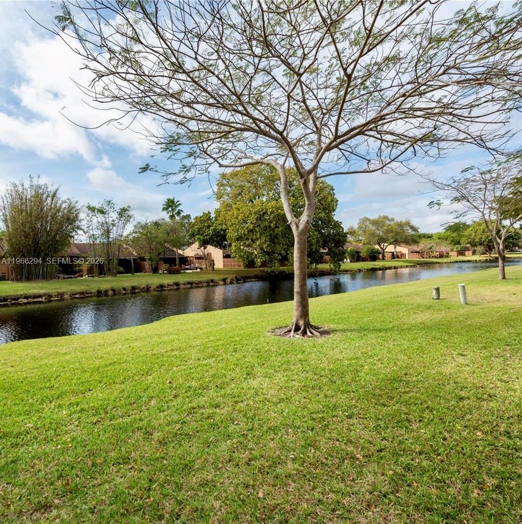 A grassy lawn leads to a canal lined with trees and residential buildings — 7924 NW 10th St, Plantation FL 33322, PLANTATION, FL