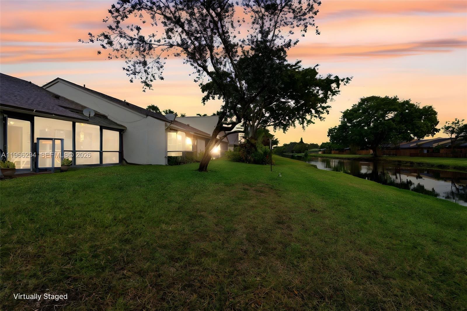 A view of the back of a house with a lawn and a canal — 7924 NW 10th St, Plantation FL 33322, PLANTATION, FL