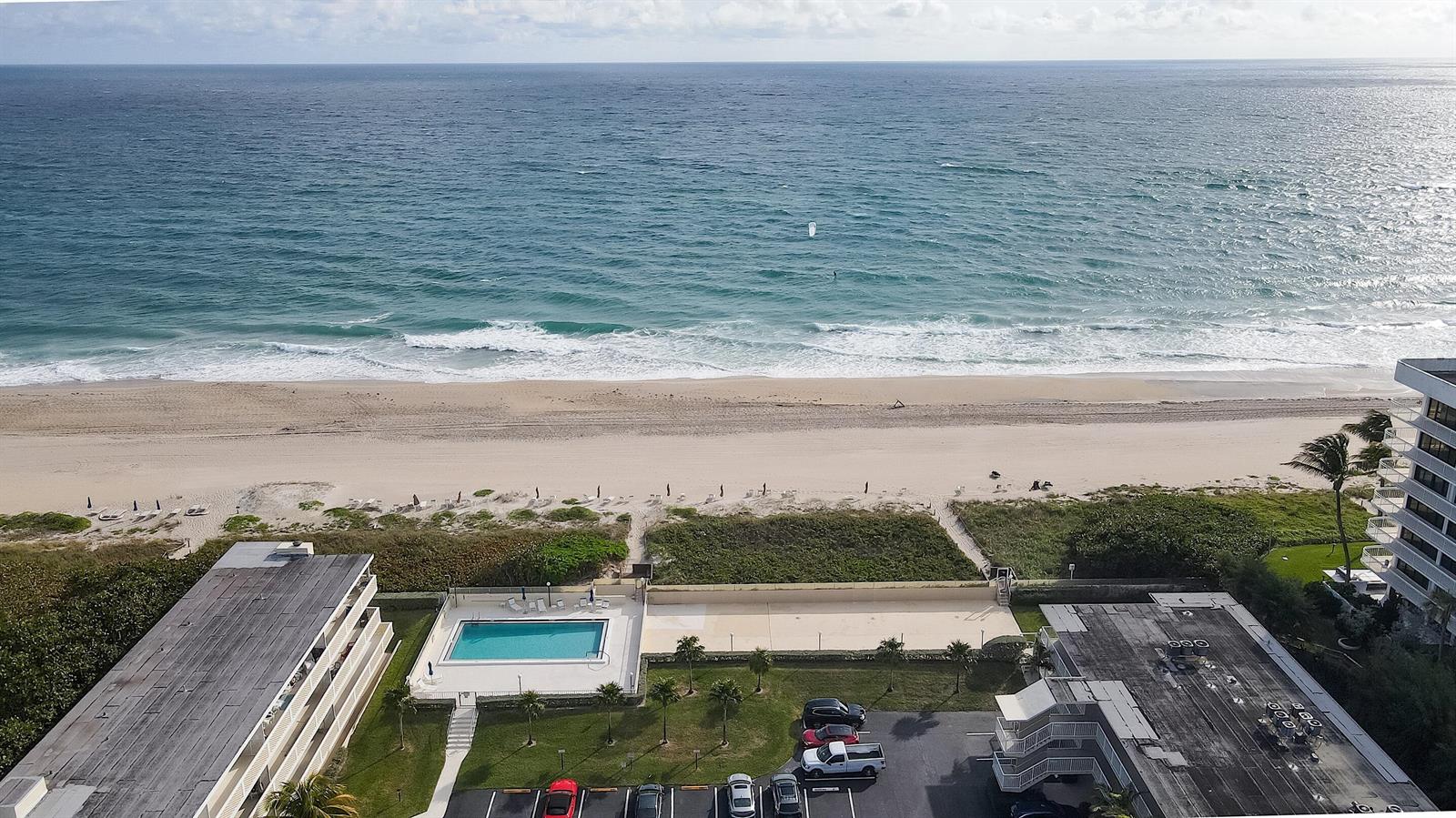 An aerial view shows a beachfront property with a swimming pool, parking lot, and ocean — 2565 S Ocean Boulevard # 208, Palm Beach FL 33480, PALM BEACH, FL