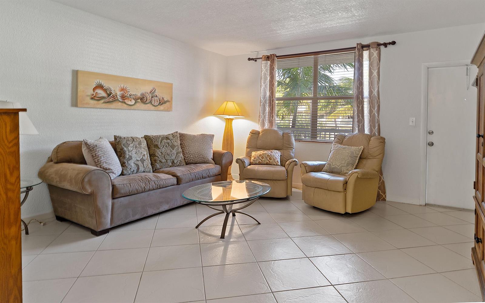 A living room features a brown sofa, two leather recliners, a glass coffee table, and tile flooring — 2565 S Ocean Boulevard # 208, Palm Beach FL 33480, PALM BEACH, FL