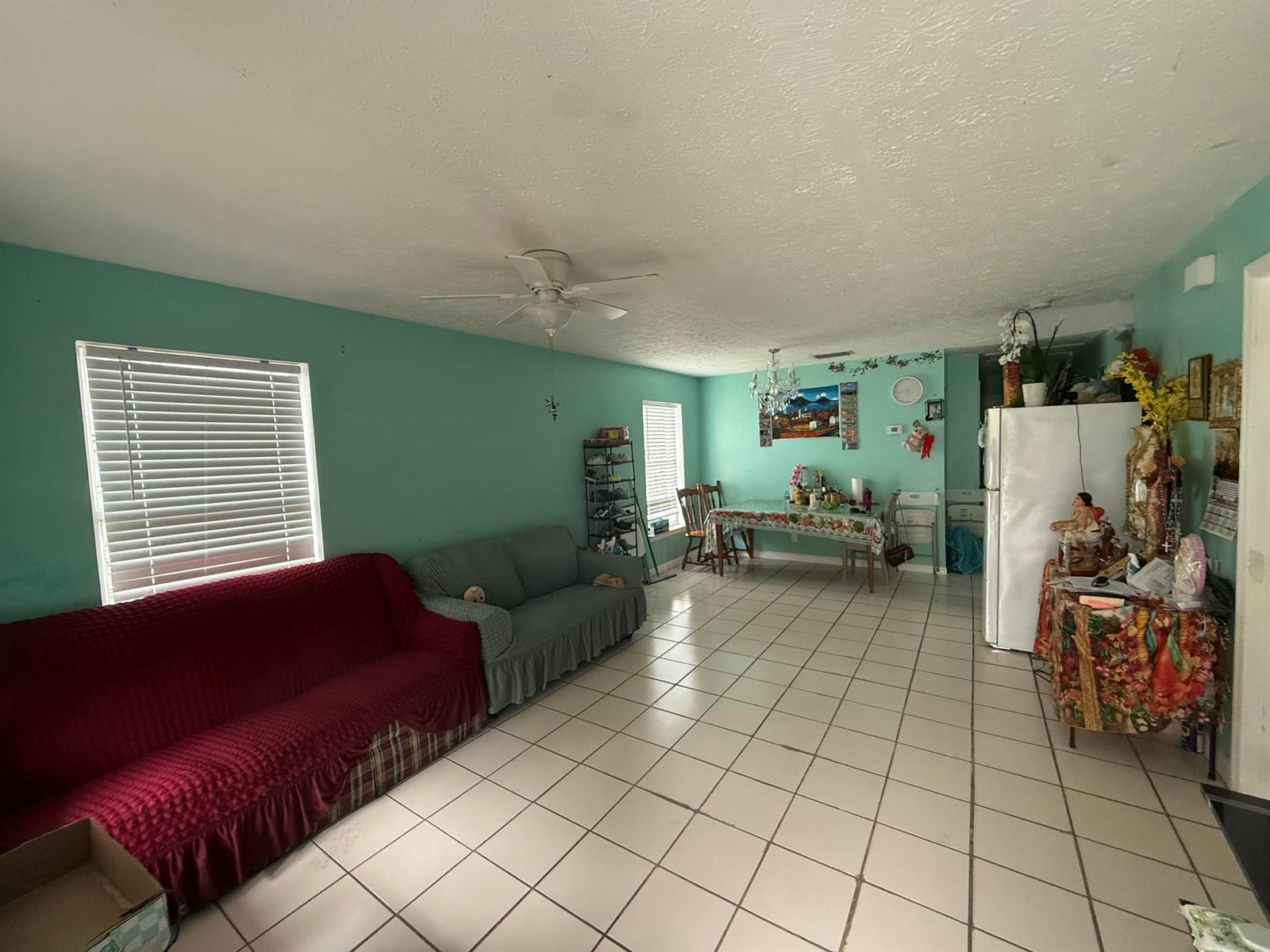A living and dining area features teal walls, white tile flooring, and a ceiling fan — 14765 SW 172nd Avenue, FL 34956, FL