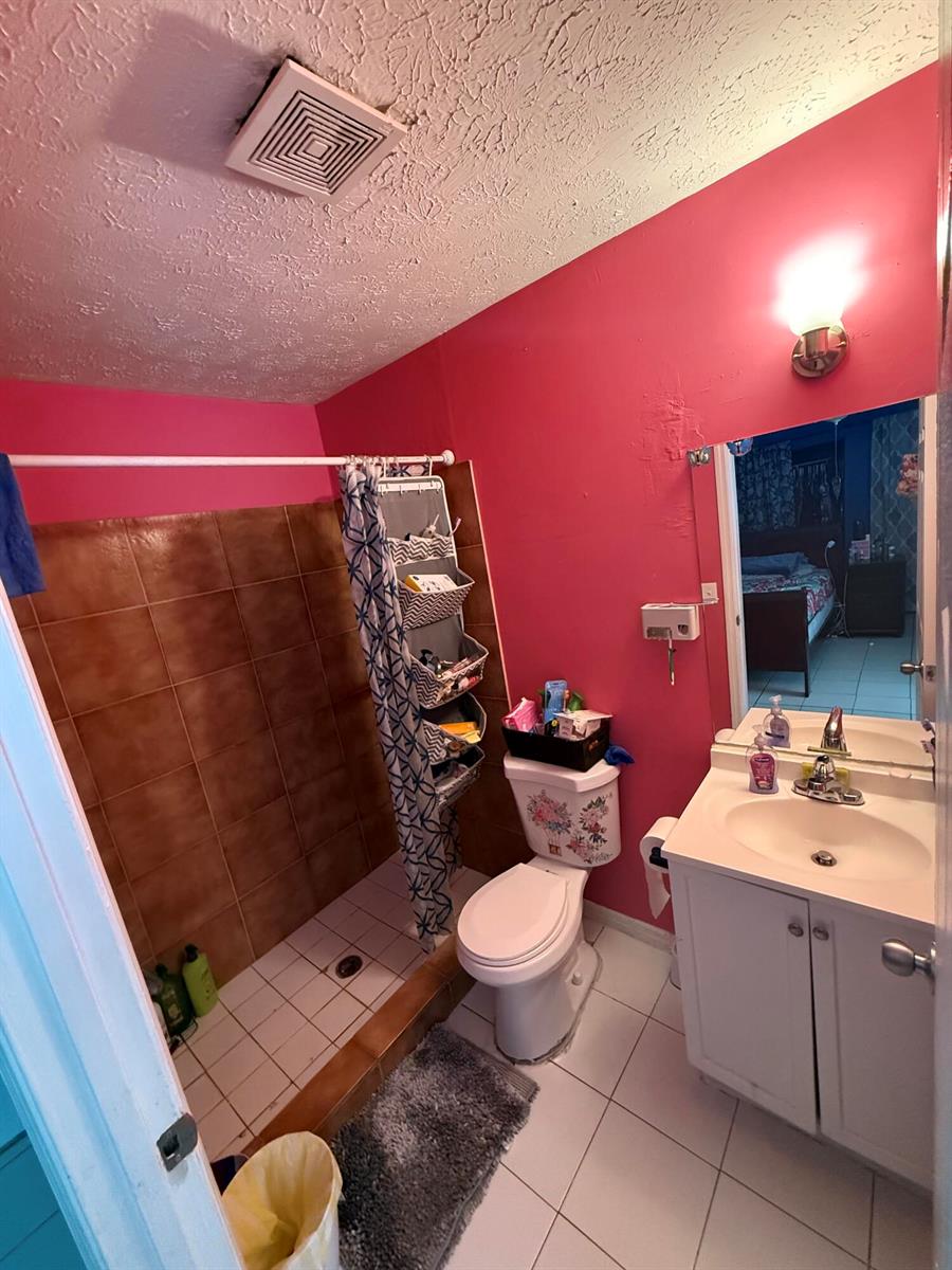 A bathroom with bright pink walls, a tiled walk-in shower, and a white vanity — 14765 SW 172nd Avenue, FL 34956, FL