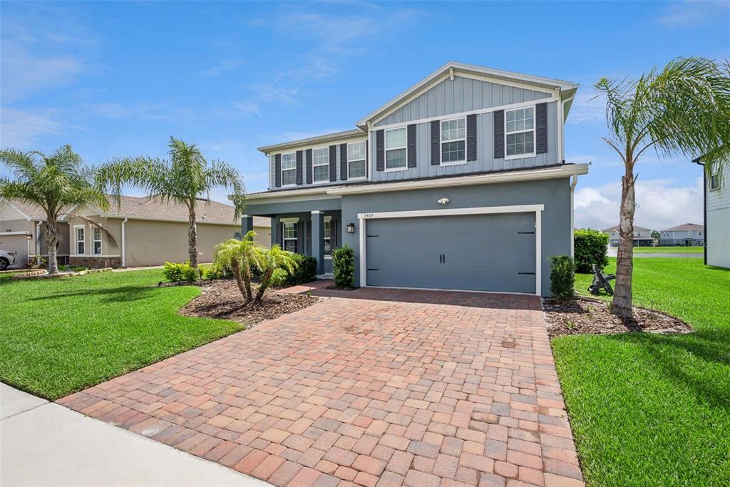 A two-story house with a gray exterior, a brick paver driveway, and palm trees — 3969 CLIPSTONE PLACE, SANFORD, FL