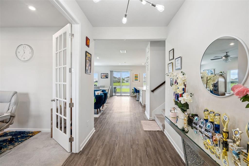 A hallway with wood-look flooring leads from an entryway past a staircase to a living area — 3969 CLIPSTONE PLACE, SANFORD, FL