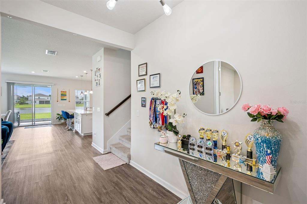 A hallway features a mirrored console table with trophies, a round mirror, and stairs — 3969 CLIPSTONE PLACE, SANFORD, FL