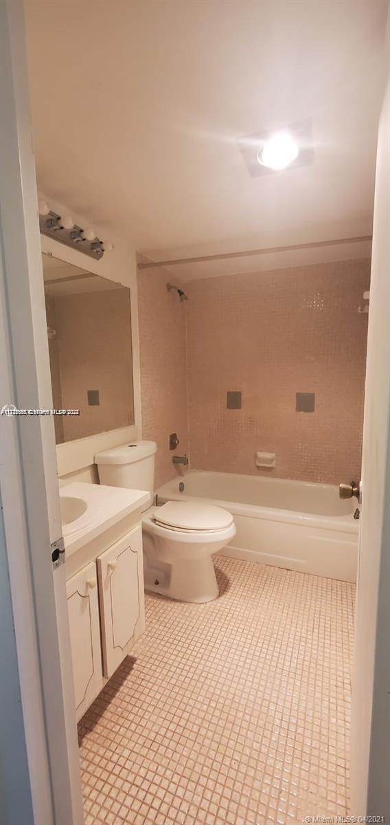 A bathroom features a white vanity, a toilet, and a bathtub with pink tiled walls — 385 Fanshaw # J, Boca Raton FL 33434, BOCA RATON, FL