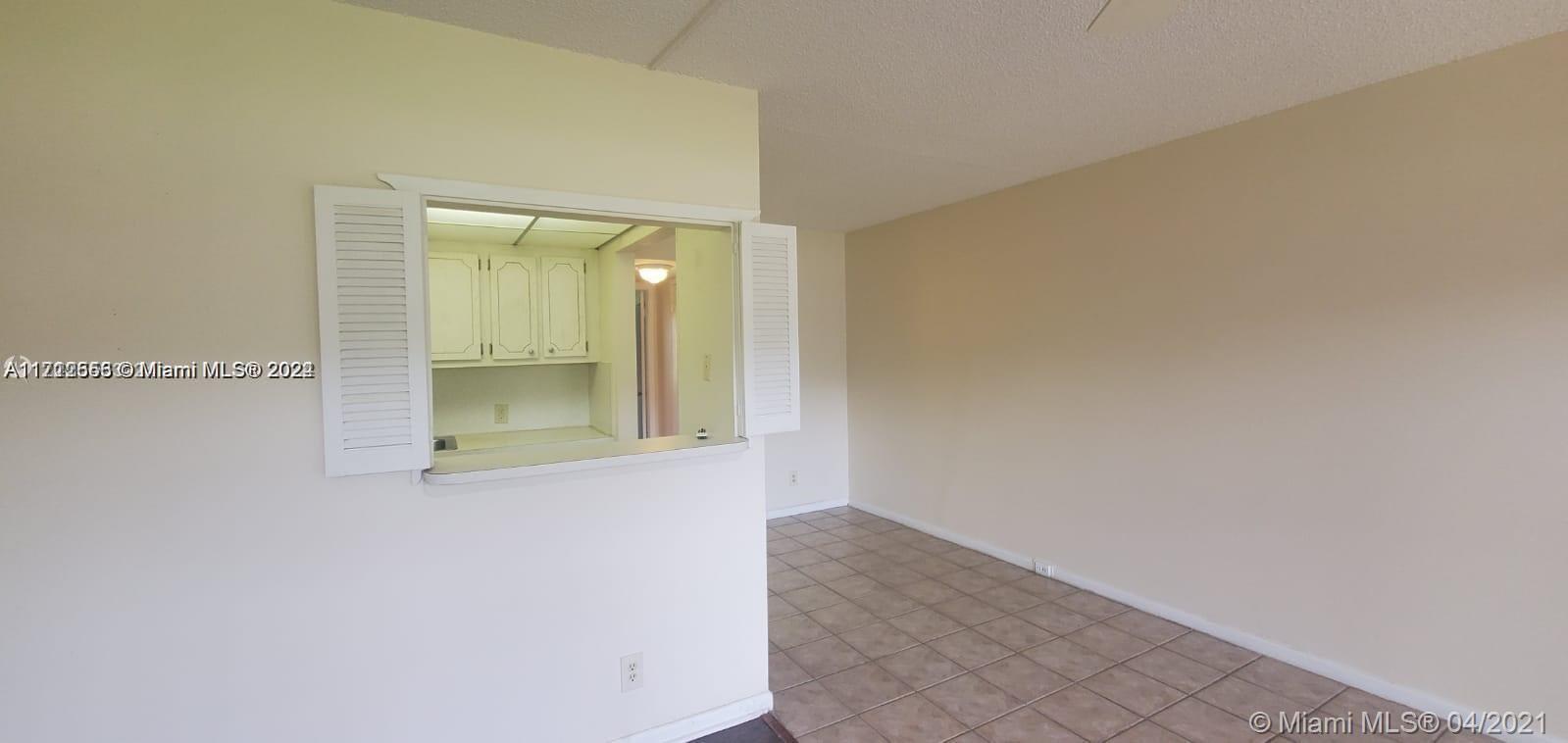 A view from a living area looking through a pass-through window into a kitchen — 385 Fanshaw # J, Boca Raton FL 33434, BOCA RATON, FL