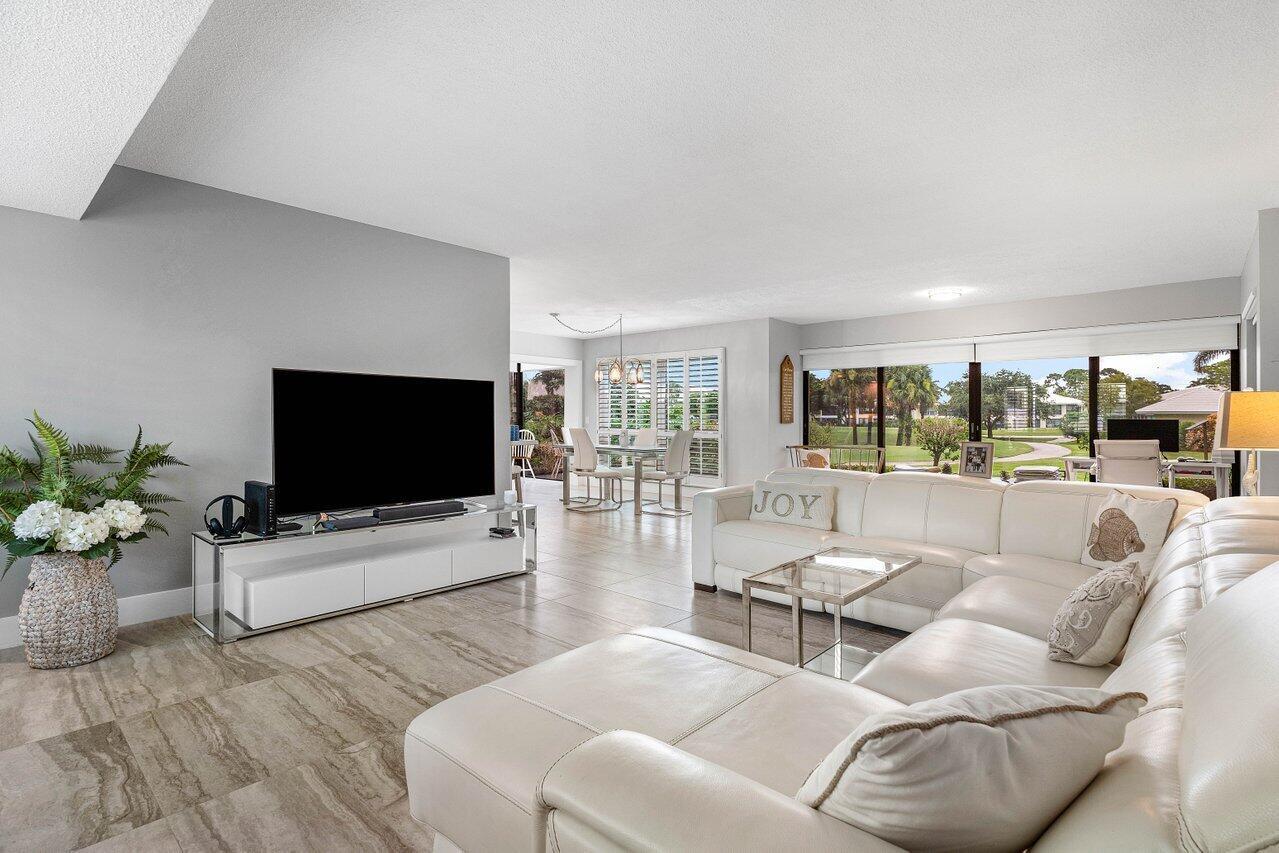 A living room features a white sectional sofa, a television on a stand, and tile flooring — 3665 Quail Ridge Drive # B, Boynton Beach FL 33436, BOYNTON BEACH, FL
