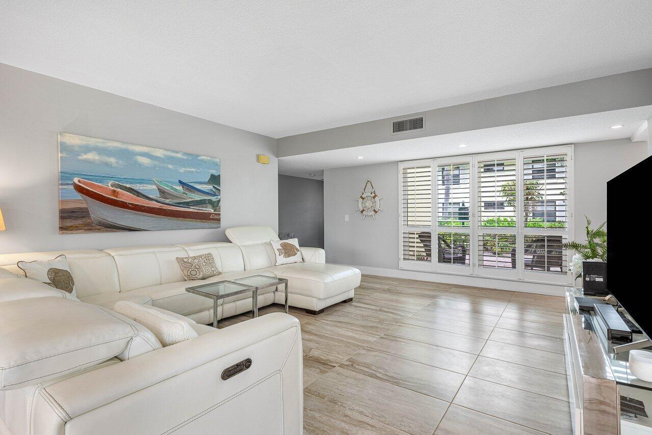 A living room features a white sectional sofa, tile flooring, and a coastal-themed wall painting — 3665 Quail Ridge Drive # B, Boynton Beach FL 33436, BOYNTON BEACH, FL
