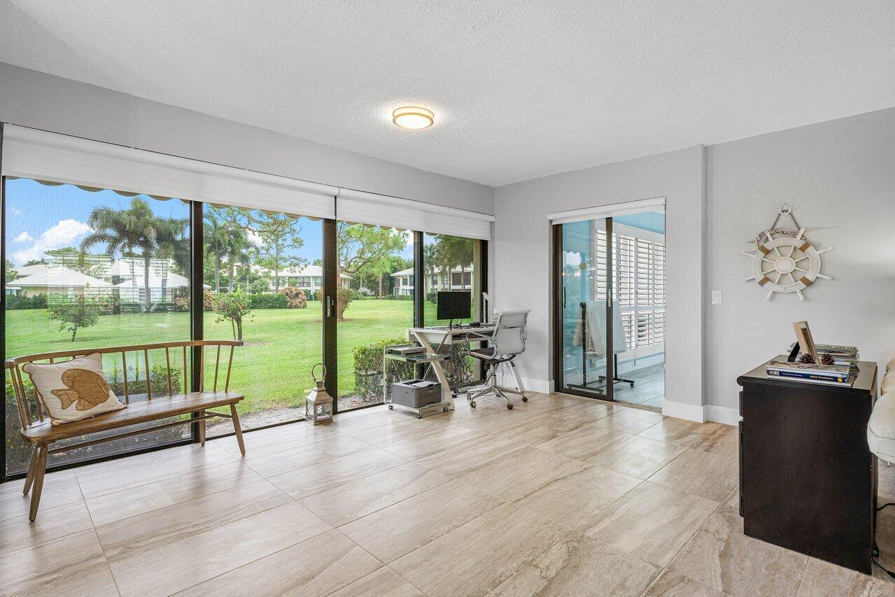 A bright room with tile floors, a desk, a bench, and large sliding glass doors — 3665 Quail Ridge Drive # B, Boynton Beach FL 33436, BOYNTON BEACH, FL