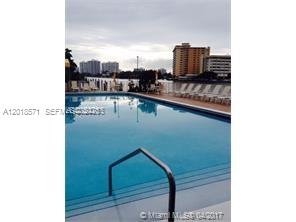 An outdoor swimming pool with a metal handrail overlooks a waterfront area with lounge chairs — 1833 S Ocean Dr # 805, Hallandale Beach FL 33009, HALLANDALE BEACH, FL