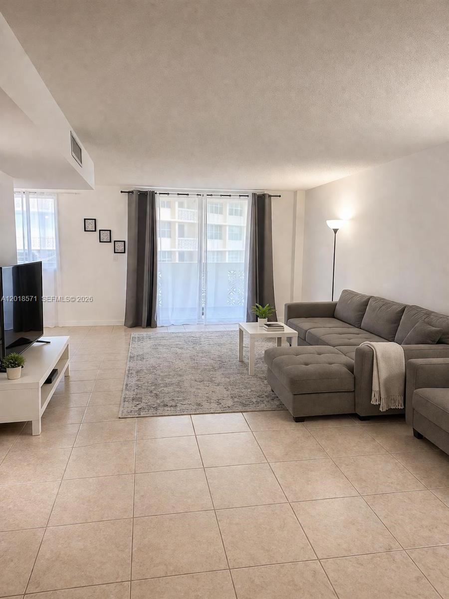 A living room features tile flooring, a gray sectional sofa, and sliding glass balcony doors — 1833 S Ocean Dr # 805, Hallandale Beach FL 33009, HALLANDALE BEACH, FL