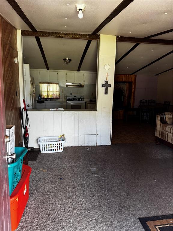 A view from a carpeted room looking into a kitchen with white cabinets — 373 RONALD STREET, COCOA, FL