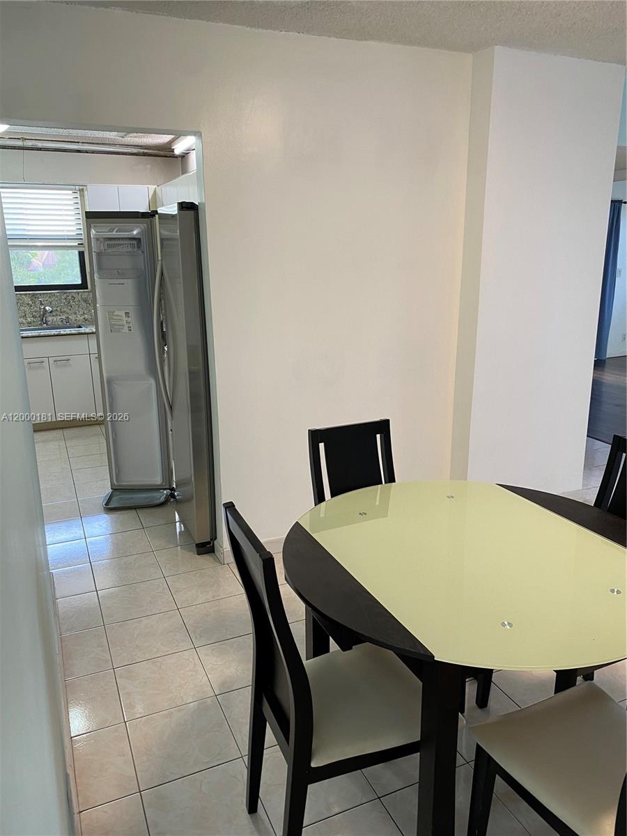 A dining area with a round table and chairs sits adjacent to a tiled kitchen — 1900 Diana Dr # 3D, Hallandale Beach FL 33009, HALLANDALE BEACH, FL