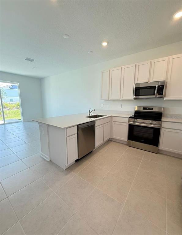A kitchen with white cabinets, stainless steel appliances, and a central island with a sink — 2633 SKYLINE LOOP, KISSIMMEE, FL
