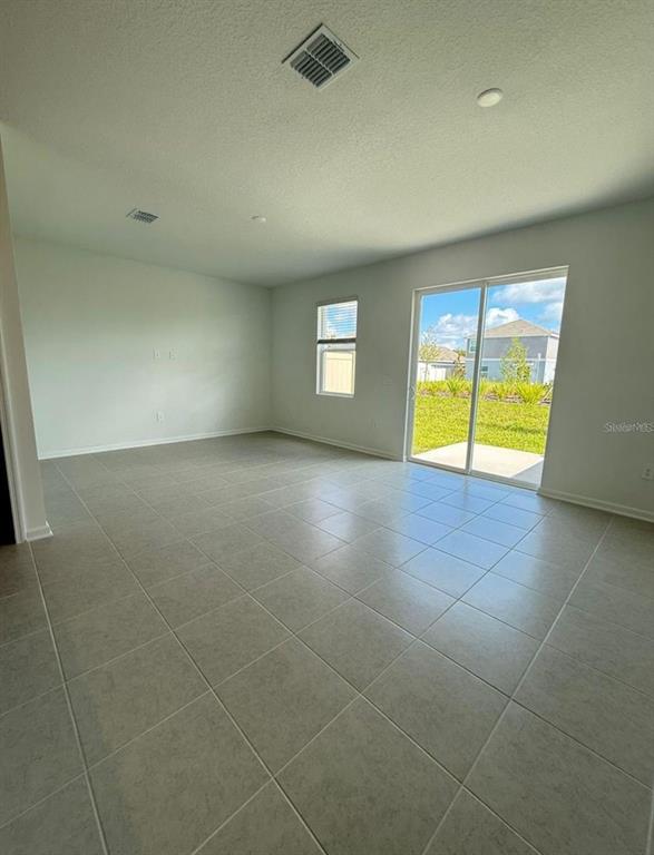 An empty room with light-colored tile flooring, a window, and sliding glass doors to outside — 2633 SKYLINE LOOP, KISSIMMEE, FL