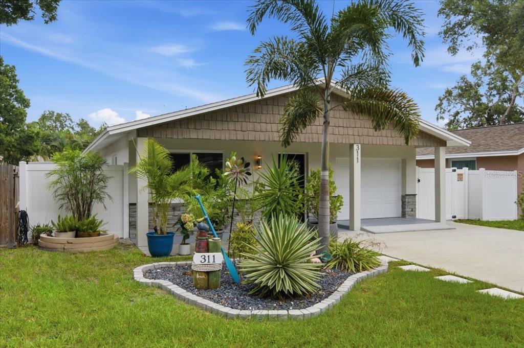 A single-story house with a white garage, palm tree, and landscaped front yard — 311 45TH AVENUE N, ST PETERSBURG, FL