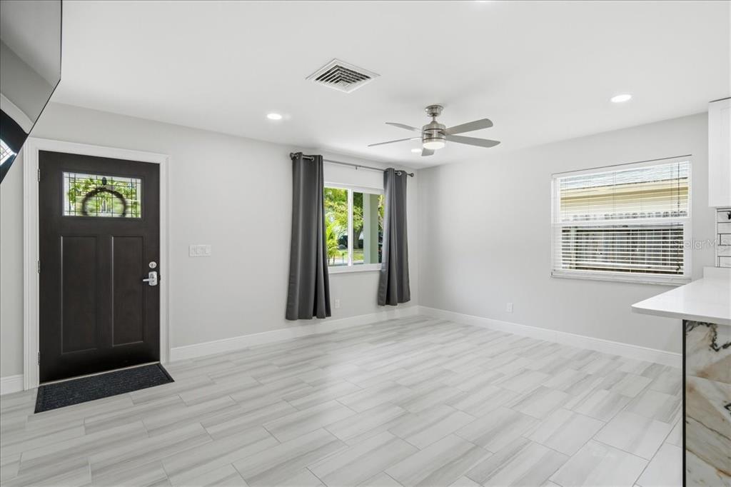 A bright room with light gray tile flooring, a dark front door, and ceiling fan — 311 45TH AVENUE N, ST PETERSBURG, FL