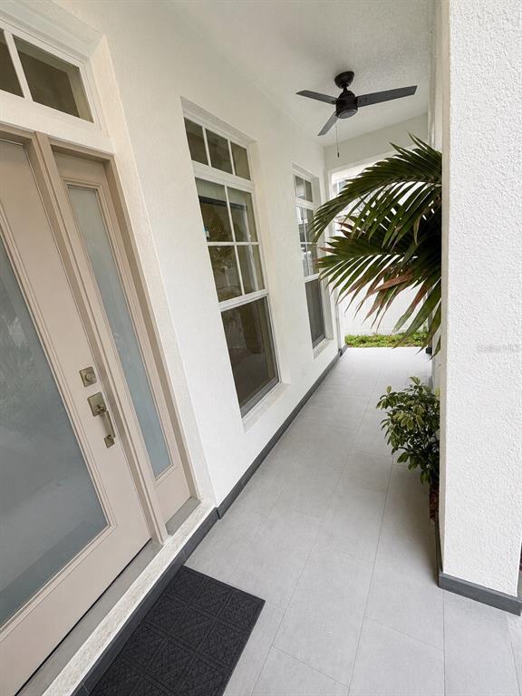 A covered entryway features a glass-paneled door, light-colored tile flooring, and a ceiling fan — 630 3RD AVENUE S, ST PETERSBURG, FL