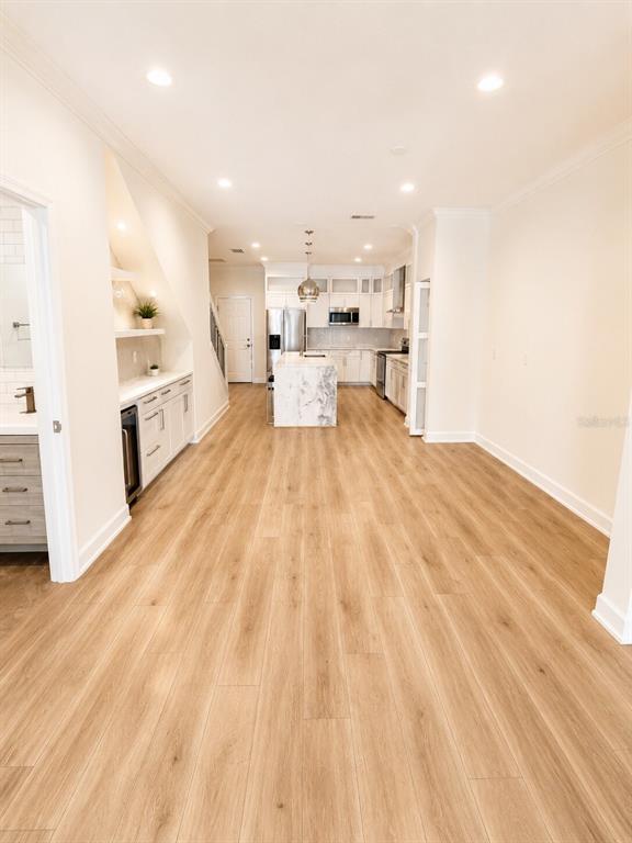 A bright, open-concept kitchen features light wood flooring, white cabinetry, and a marble-topped island — 630 3RD AVENUE S, ST PETERSBURG, FL