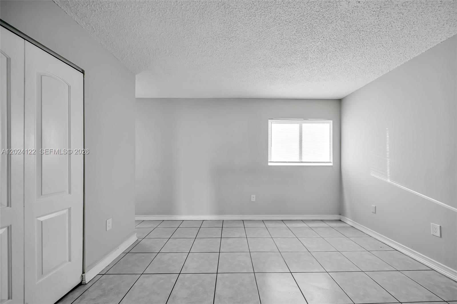 An empty room features light gray walls, white tile flooring, and a white closet door — 2011 Bay Dr # 12, Miami Beach FL 33141, MIAMI BEACH, FL