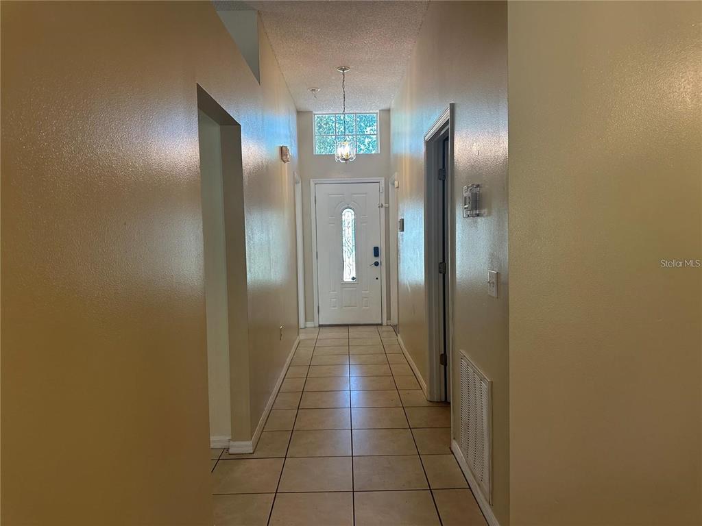 A tiled entryway features a high ceiling, a chandelier, and a white front door — 17432 WOODCREST WAY, CLERMONT, FL