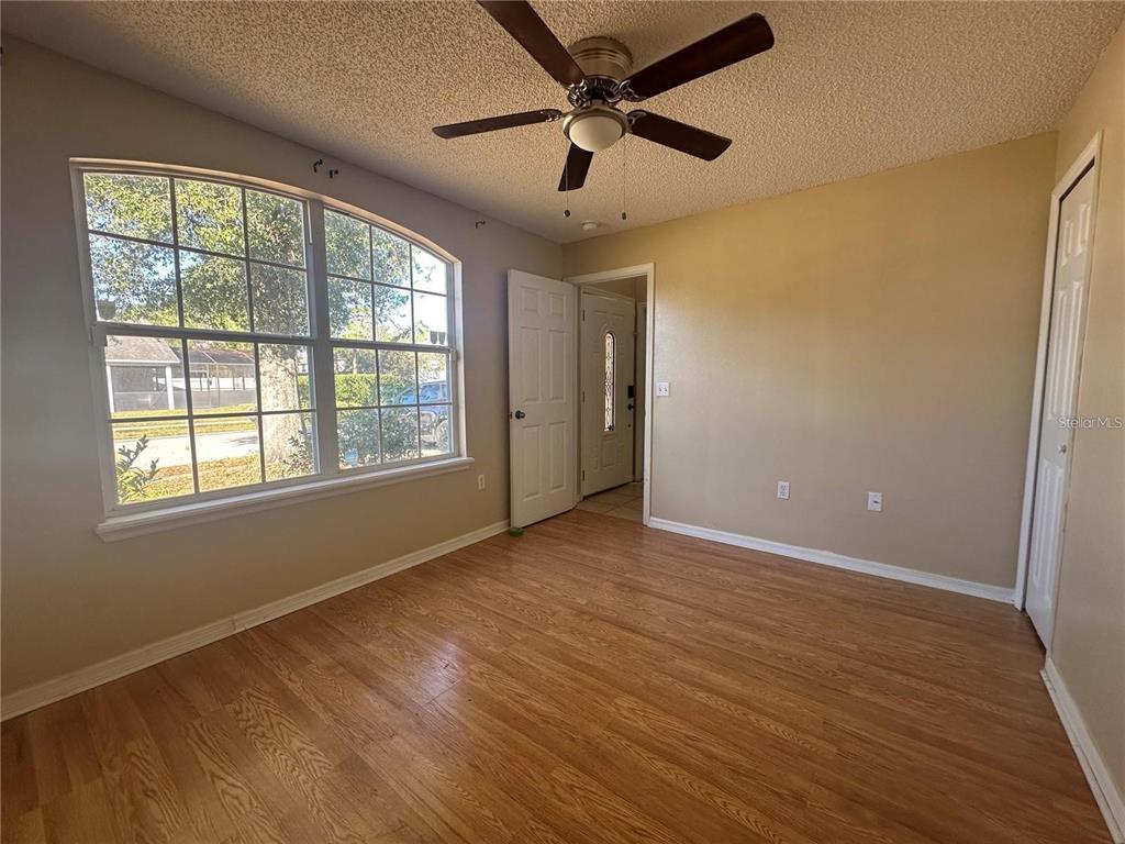 An empty room with wood-look flooring, a ceiling fan, and a large arched window — 17432 WOODCREST WAY, CLERMONT, FL