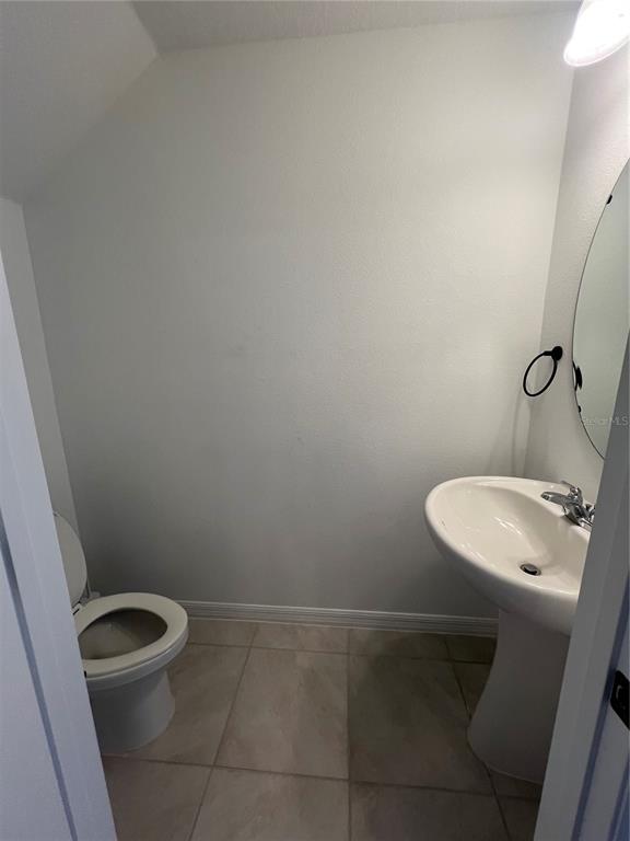 A small bathroom features a pedestal sink, a toilet, and light-colored floor tiles — 117 MANDOVI STREET, DAVENPORT, FL