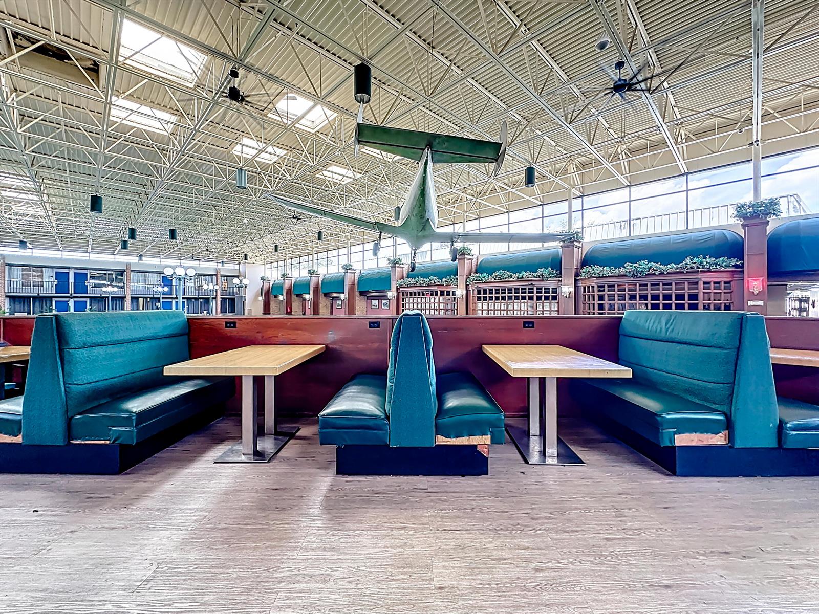 A restaurant dining area features teal booths, wooden tables, and an airplane suspended overhead — 910 Suemac Road, Jacksonville FL 32254, JACKSONVILLE, FL