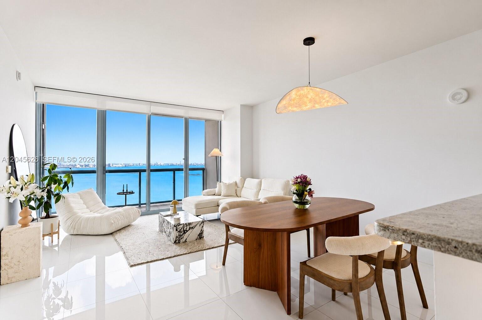 A bright living and dining area features white tile floors, modern furniture, and floor-to-ceiling windows — 601 NE 36th St # 3011, Miami FL 33137, MIAMI, FL