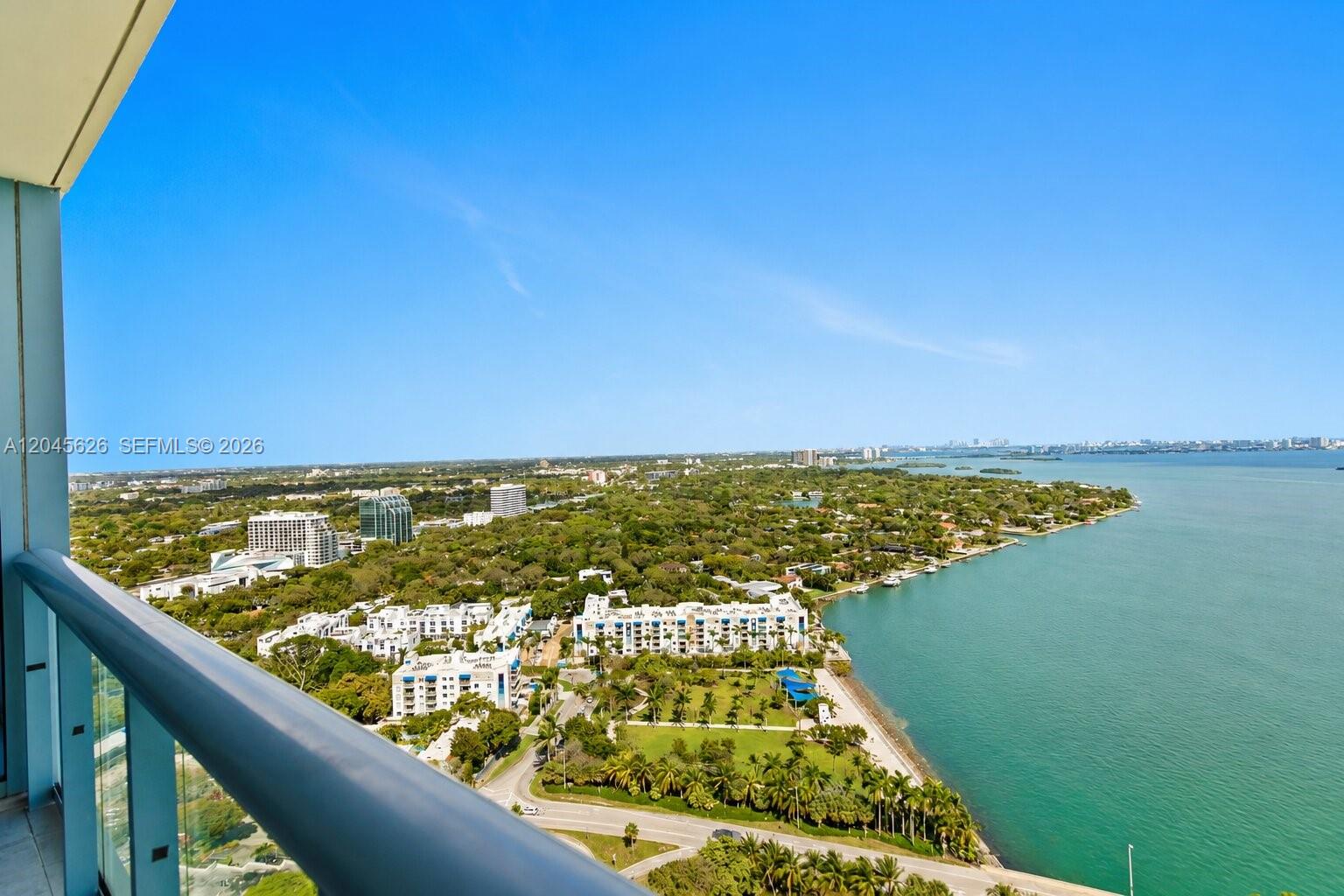 A high-angle view from a balcony overlooking a coastal city, greenery, and the ocean — 601 NE 36th St # 3011, Miami FL 33137, MIAMI, FL