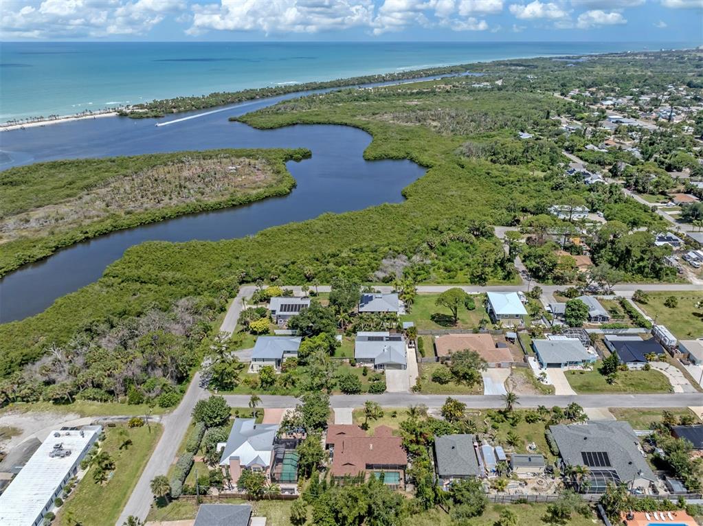 An aerial view shows a residential neighborhood bordering a large mangrove-filled waterway and the ocean — 1533 FUNDY ROAD, VENICE, FL