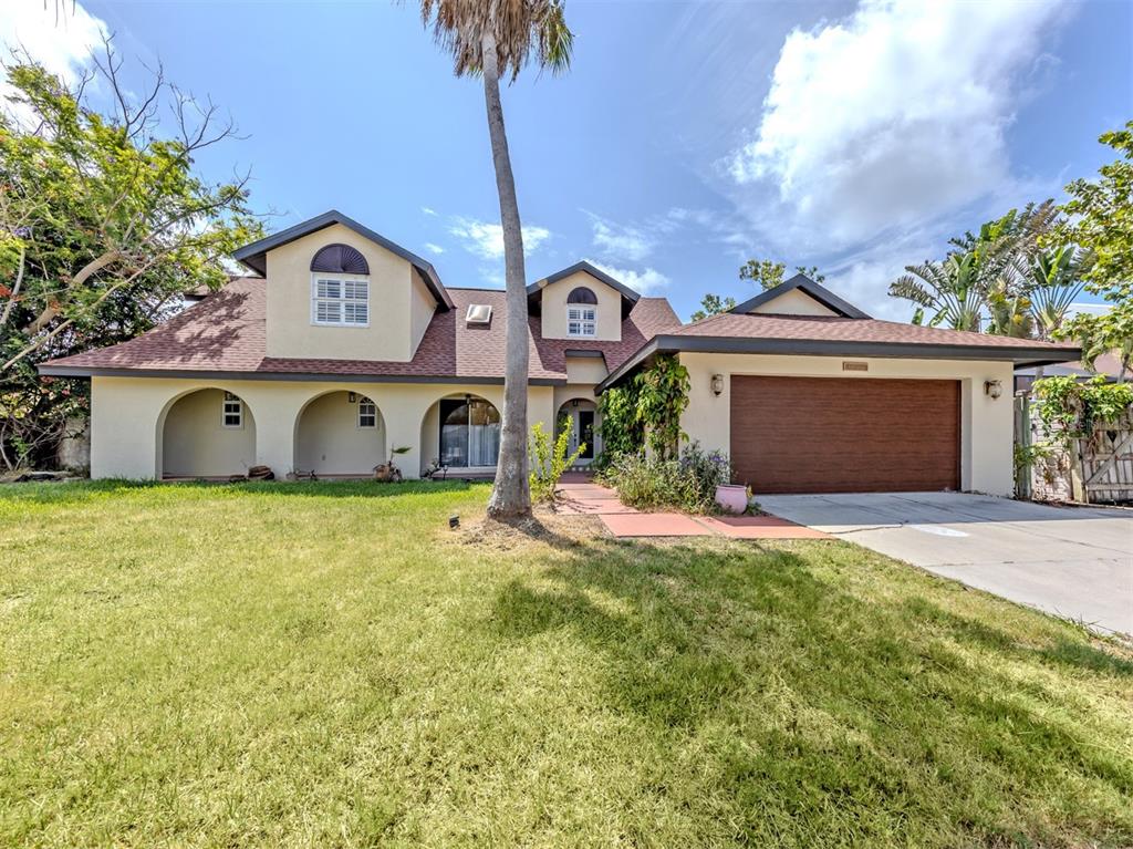 A two-story house with a brown shingled roof, arched entryways, and an attached garage — 1533 FUNDY ROAD, VENICE, FL