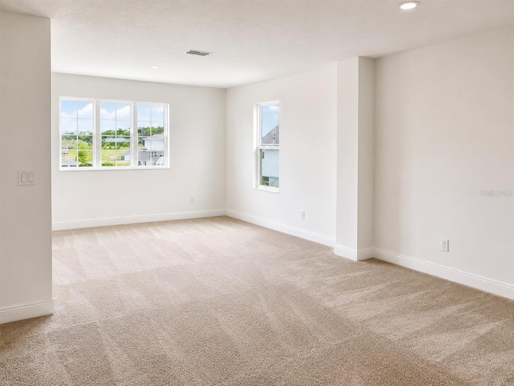An empty room with beige carpet, white walls, and two windows overlooking a neighborhood — 4932 OLIVIA COURT, ST CLOUD, FL