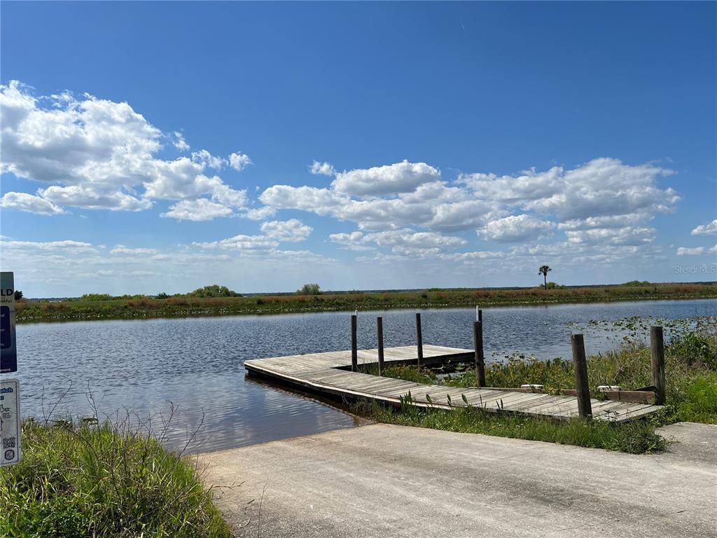A concrete boat ramp leads to a wooden dock on a calm lake — 901 AZALEA DRIVE, INDIAN LAKE ESTATES, FL