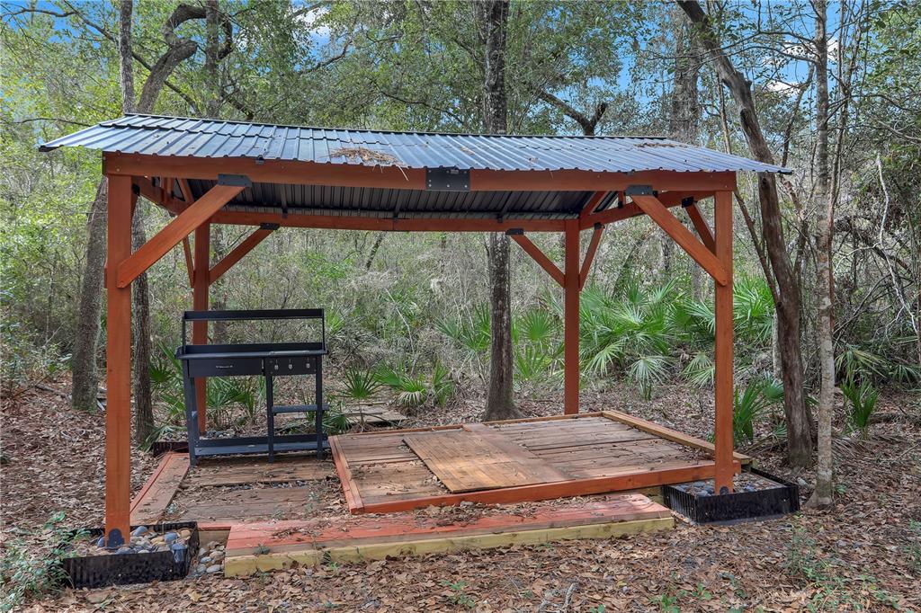 A wooden gazebo with a metal roof stands on a deck in a wooded area — 00 SE 929TH STREET, OLD TOWN, FL