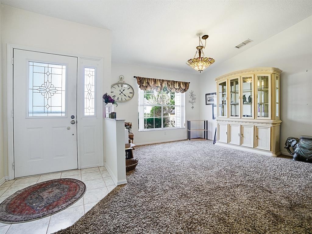 A carpeted dining room features a large china cabinet, a chandelier, and an entryway door — 5535 TANGELO STREET, LEESBURG, FL