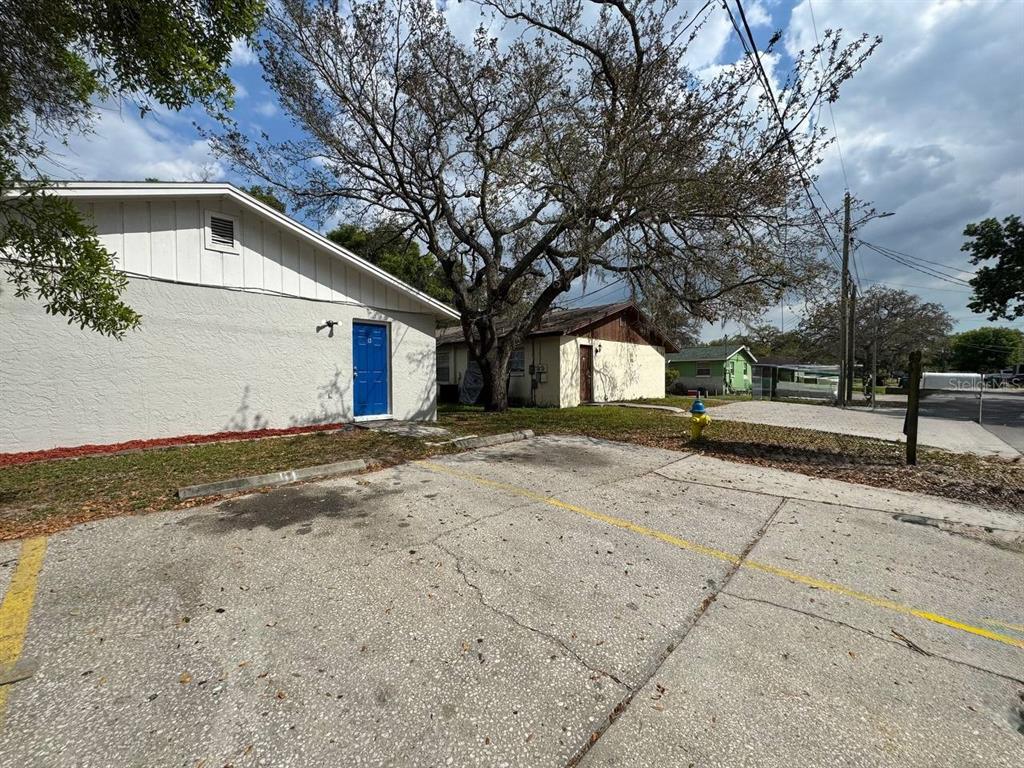 Exterior view of a single-story building with a blue door and a paved parking lot — 10015 N ASTER AVENUE UNIT B, TAMPA, FL