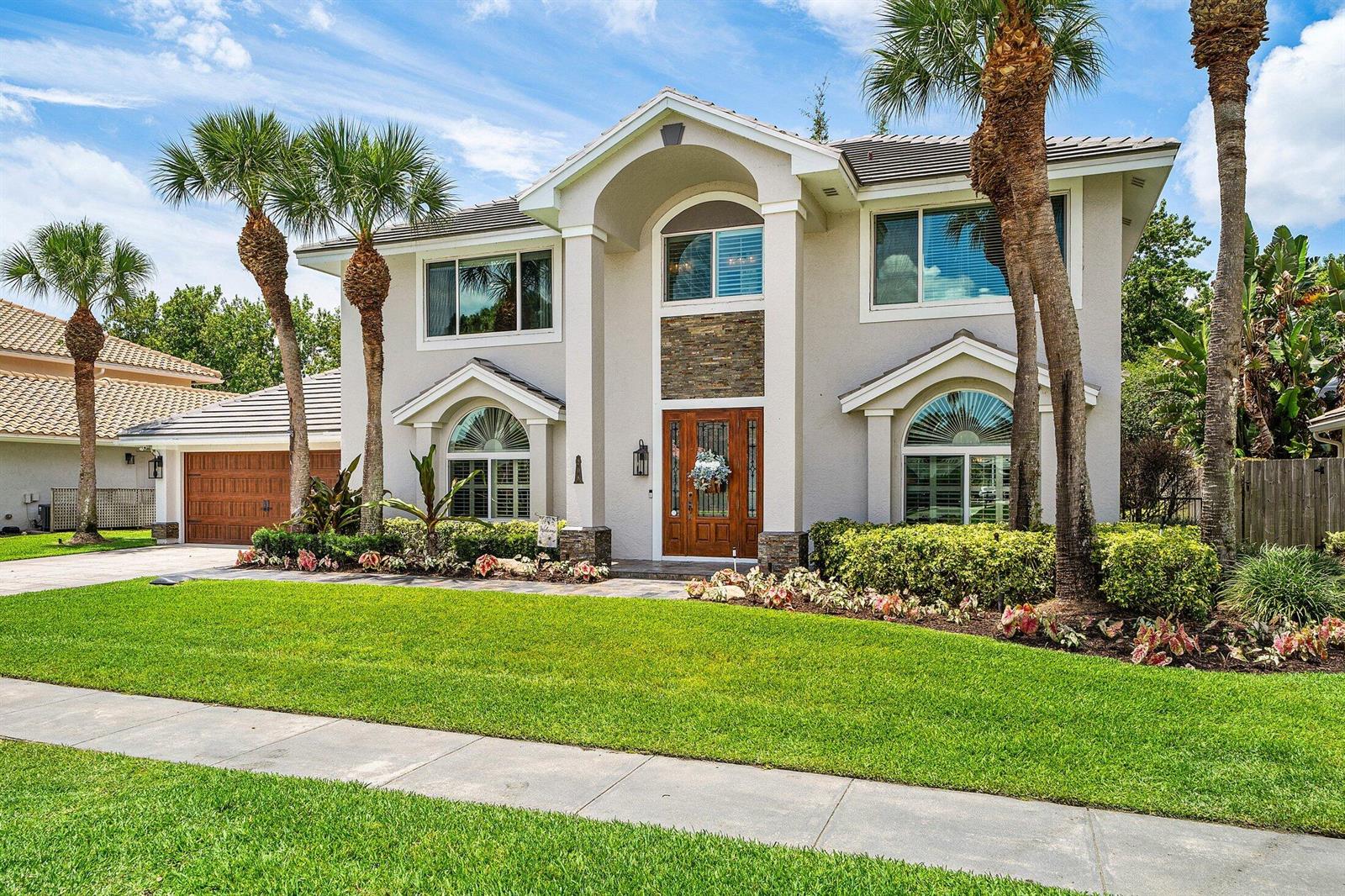A two-story suburban house with a stone-accented entryway, arched windows, and palm trees — 208 Longshore Drive, Jupiter FL 33458, JUPITER, FL