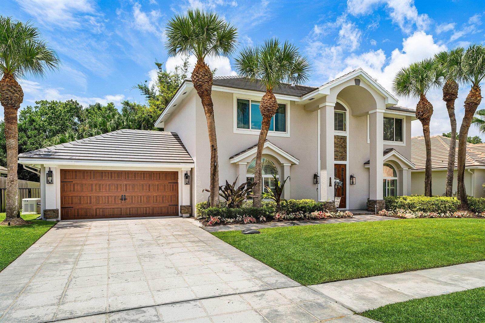 A two-story house with a brown garage door, palm trees, and a paved driveway — 208 Longshore Drive, Jupiter FL 33458, JUPITER, FL