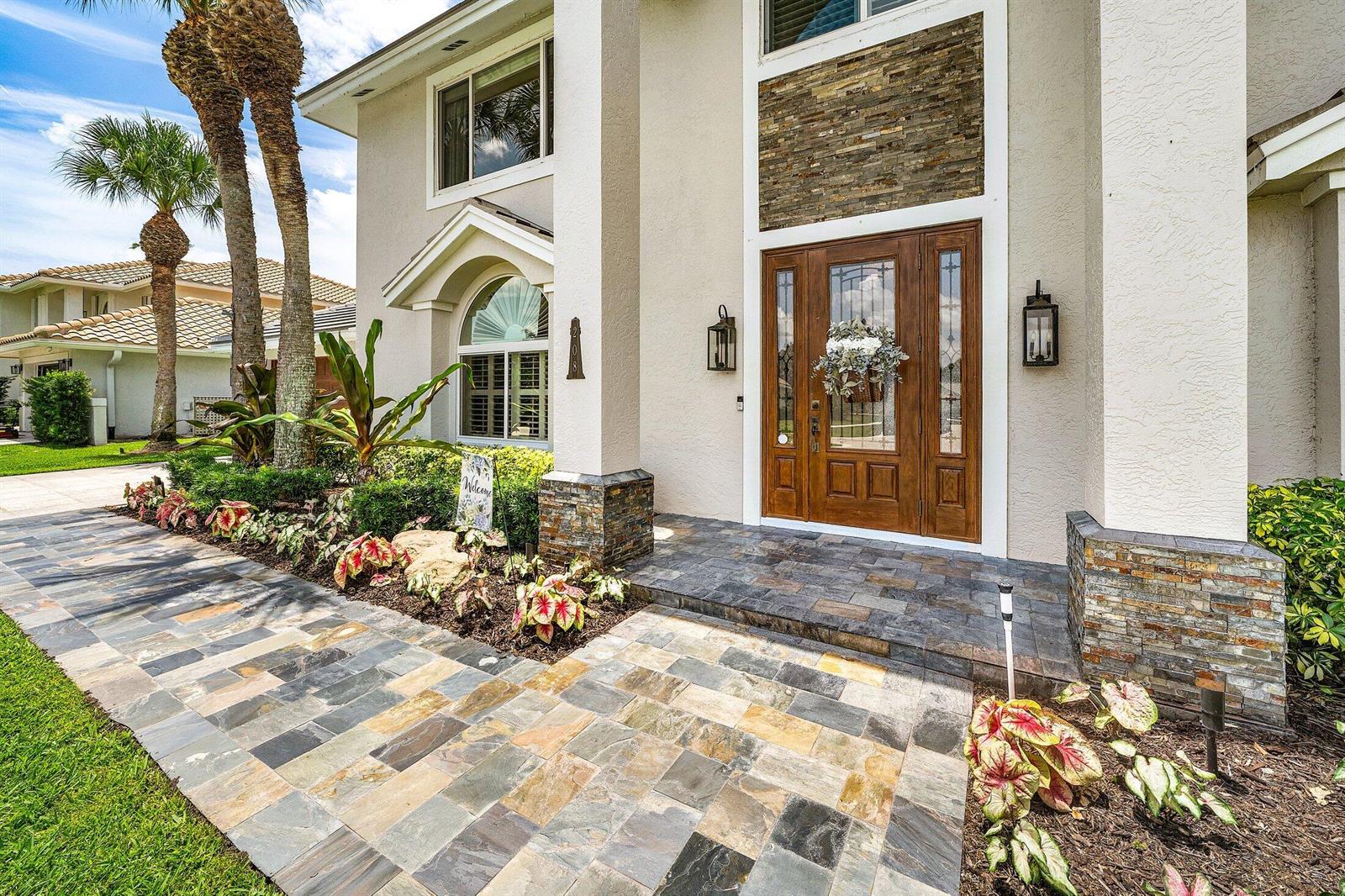A paved walkway leads to the front entrance of a house with stone accents — 208 Longshore Drive, Jupiter FL 33458, JUPITER, FL