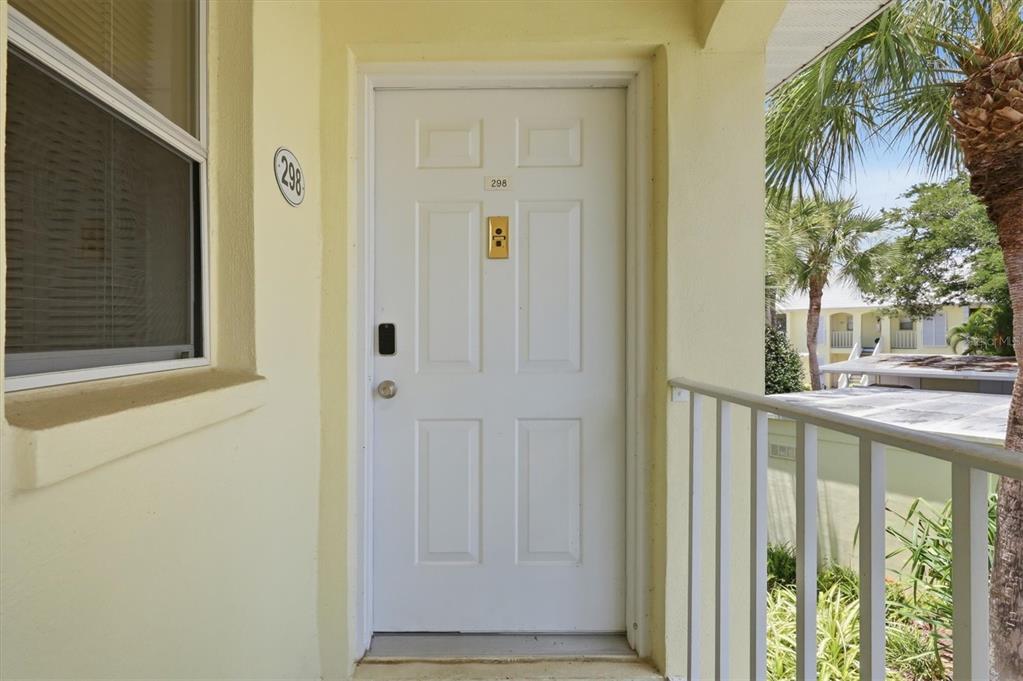 A white front door with a digital lock and a number plate on a balcony — 444 CERROMAR ROAD UNIT 298, VENICE, FL
