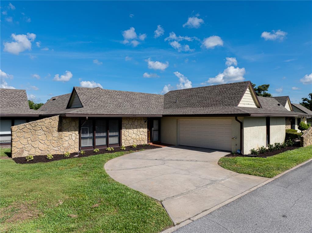 A single-story house with a stone facade, a two-car garage, and a concrete driveway — 1408 MAGELLAN CIRCLE UNIT 103, ORLANDO, FL